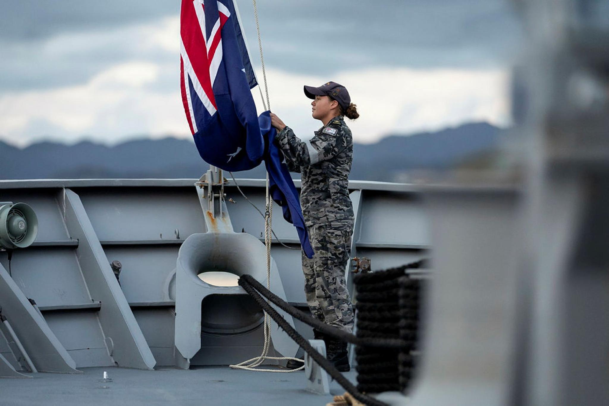 Leading Seaman Boatswains Mate Cerys Zurek lowers the Australian National Flag during a sunset ceremony whilst HMAS Stuart is alongside Joint Base Pearl Harbour Hickam, Hawaii as part of a Pacific deployment.