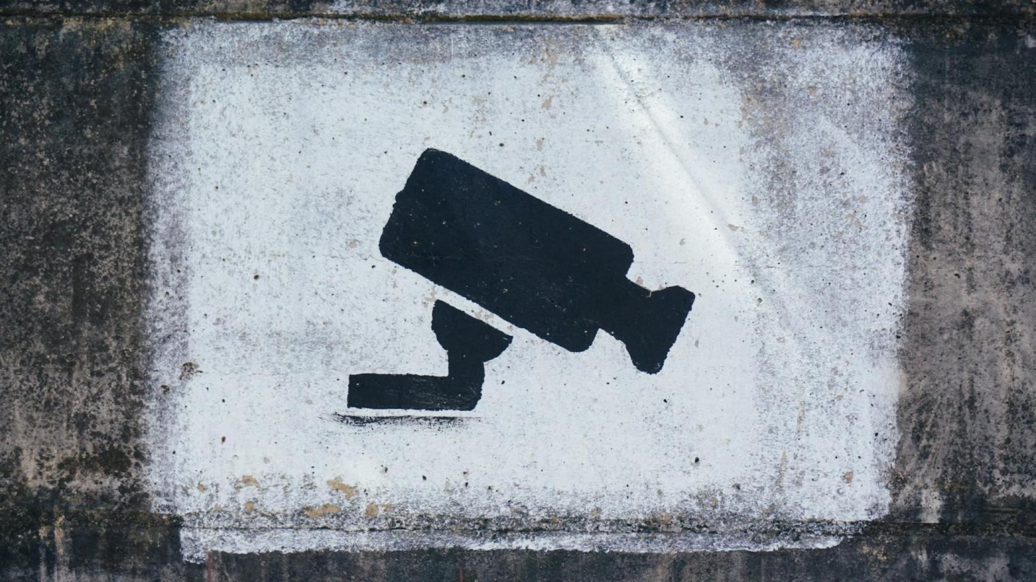 Photo of a spotlight lighting up a surveillance camera still painting on concrete wall