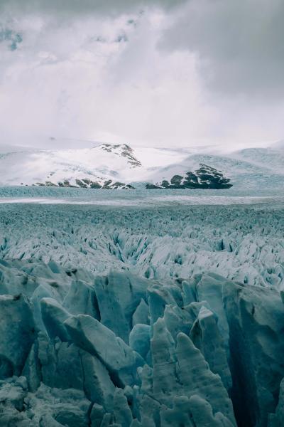 Picture of glaciers in Antartica with snowy rock mountains in the background